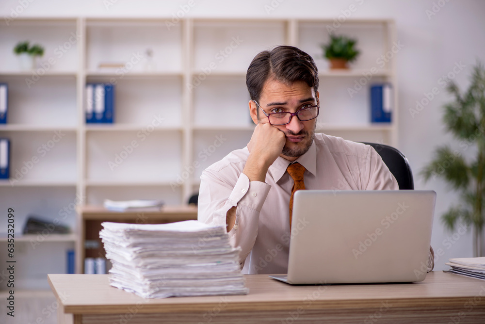 Young male employee and too much work in the office Young male employee and too much work in the office