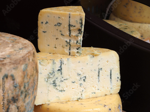 Cheese, a large piece lying on a wooden board, close-up. Natural products, the concept of healthy nutrition.