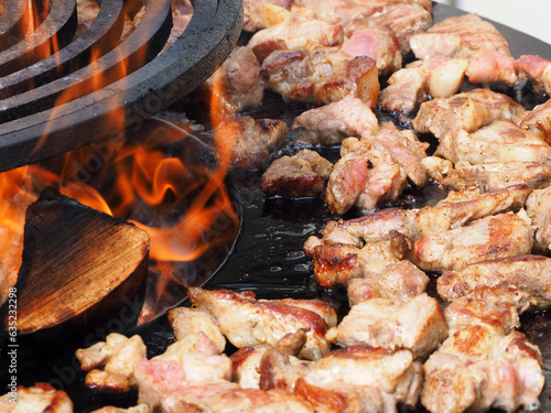 Obraz na płótnie Meat, delicious fried pieces, with a golden crust, cooked on the grill, against the background of a brazier and fire. Pieces of fried meat, close-up. w salonie