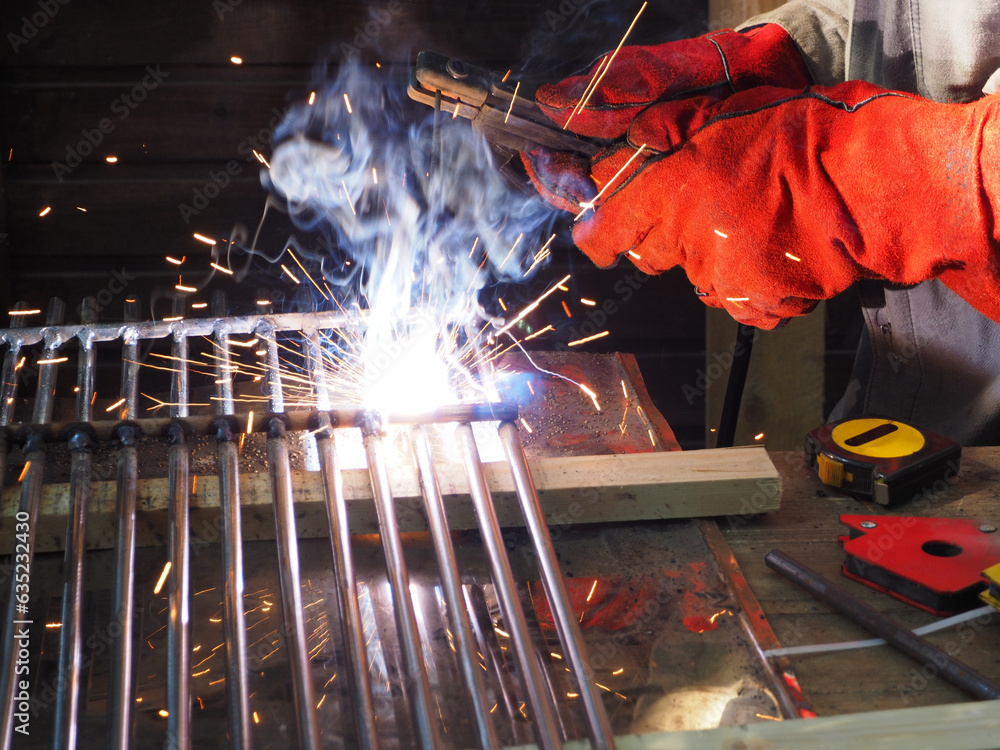 Welding work, close-up of a hand welding metal parts. The concept of locksmith work, welding production, processing of metal products.
