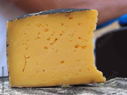 Cheese, a large piece lying on a wooden board, close-up. Natural products, the concept of healthy nutrition.