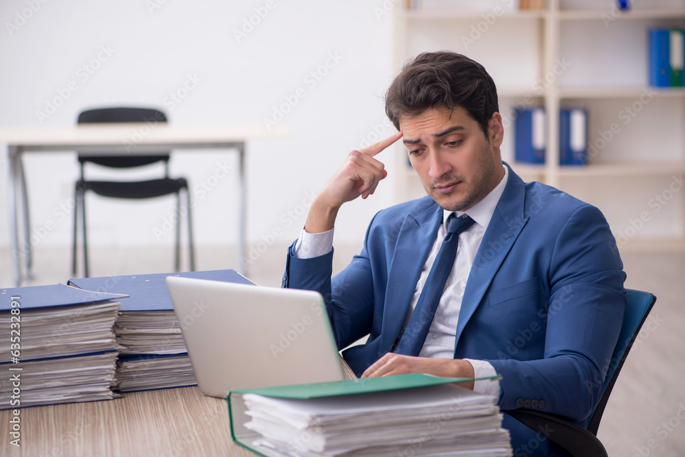 Young male employee and too much work in the office Young male employee and too much work in the office