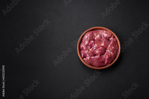 Fresh raw chicken or turkey liver in a ceramic plate with salt, spices and herbs
