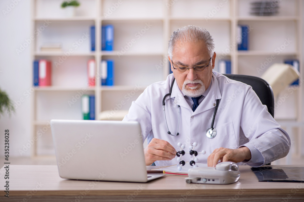 Old male doctor lecturer holding molecular model Old male doctor lecturer holding molecular model