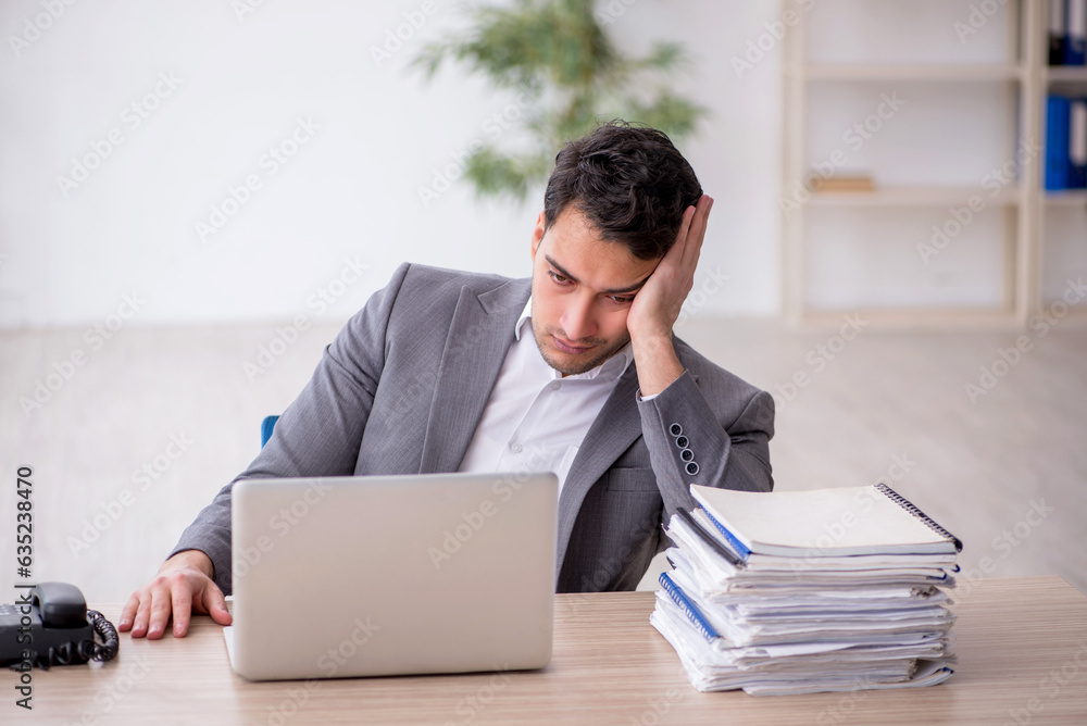 Young male employee and too much work in the office Young male employee and too much work in the office