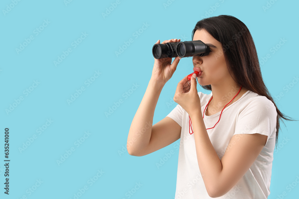 Female lifeguard with binoculars whistling on blue background Female lifeguard with binoculars whistling on blue background