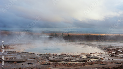Icelandic geyser in panoramic scenery near reykjavik, holes erupting and creating beautiful fountain with hot water and steam. Scandinavian crater with jet in iceland, landscape. Handheld shot.