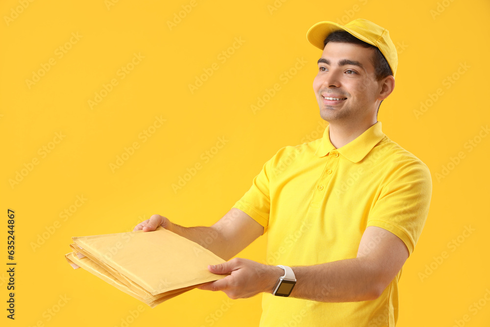 Male courier with envelopes on yellow background Male courier with envelopes on yellow background