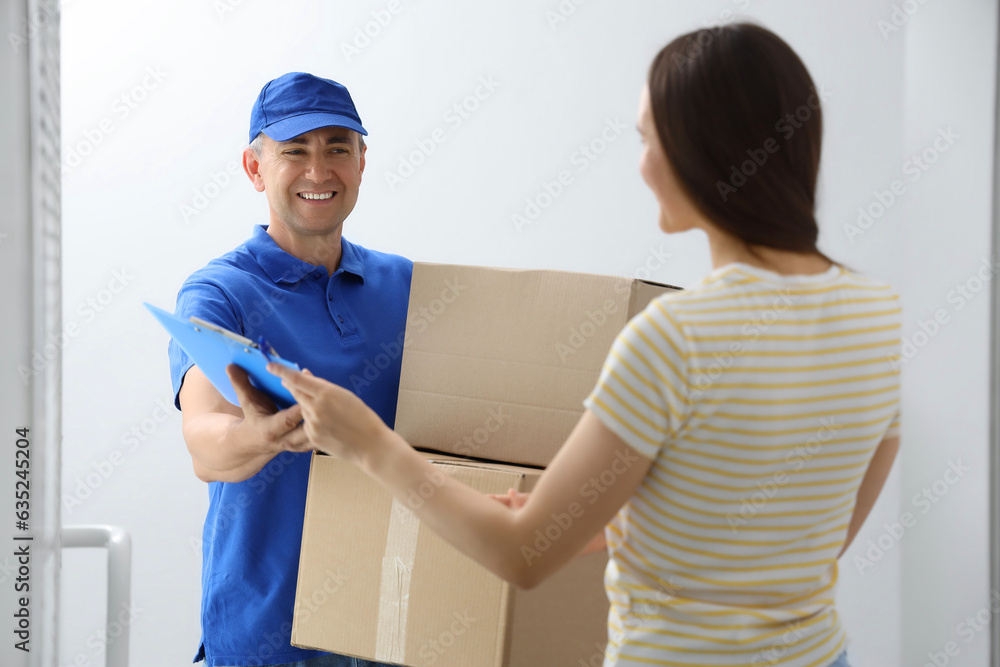 Young woman receiving parcels from courier in stairway Young woman receiving parcels from courier in stairway