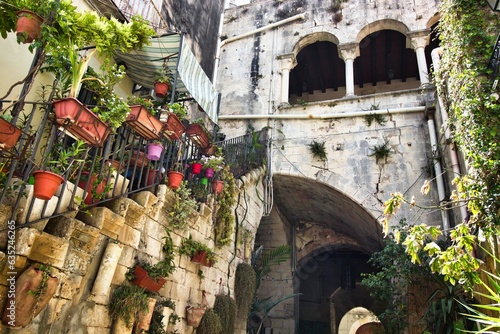 A typical old Italian courtyard with stone steps and balcony with arches © TenWit