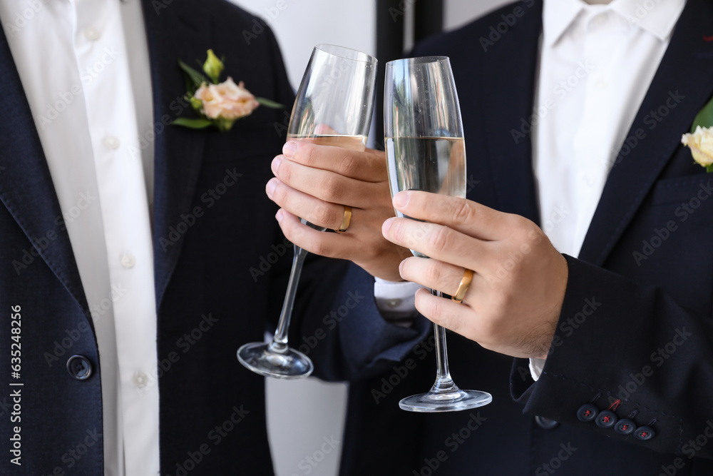 Happy gay couple with glasses of champagne on their wedding day, closeup