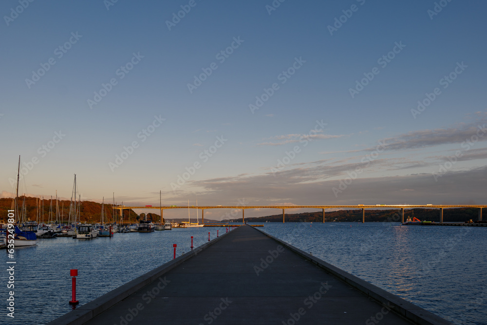Outdoor exterior view at Vejle Havn Mole and background of Vejle Fjord Bridge during twilight sky in Vejle, Denmark.
