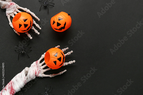Skeleton hands with pumpkins and spiders for Halloween celebration on dark background