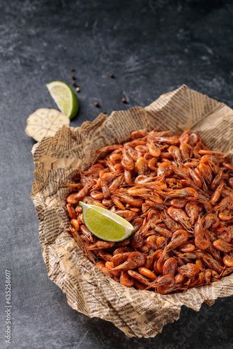 Small shrimps cooked in a bowl with lemon, garlic on a gray background