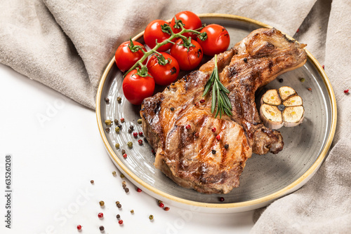 Grilled meat on a wooden board with trimmings on a light background