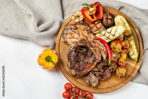 Grilled meat on a wooden board with trimmings on a light background