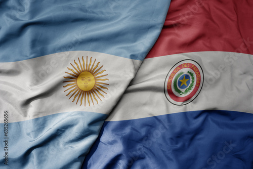 big waving realistic national colorful flag of argentina and national flag of paraguay .