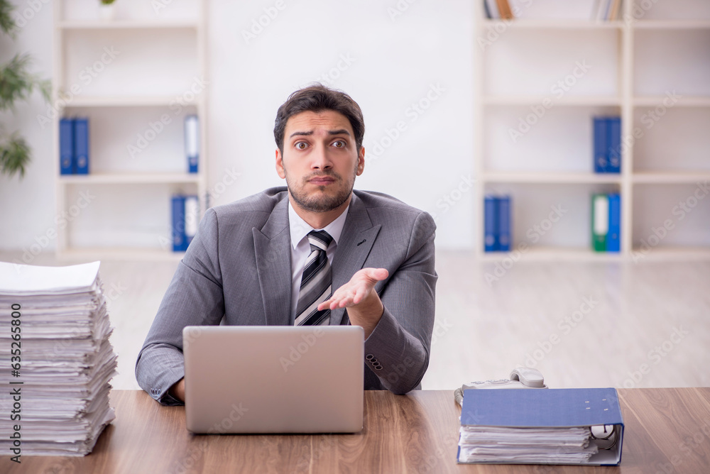 Young male employee and too much work in the office Young male employee and too much work in the office