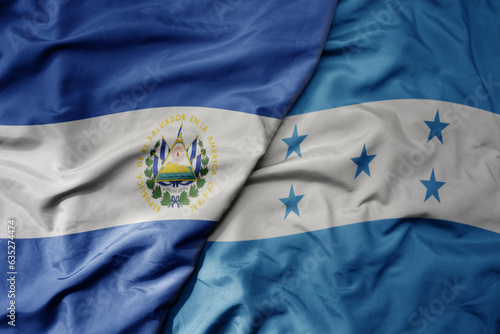 big waving realistic national colorful flag of el salvador and national flag of honduras . photo