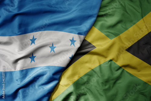 big waving realistic national colorful flag of honduras and national flag of jamaica .