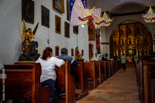 People pray on the benches of the main parish of Villa de Leyva, Colombia