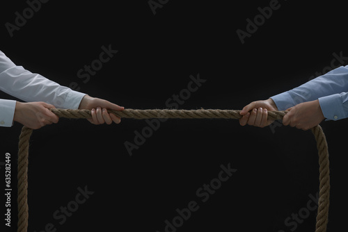 Dispute concept. Men pulling rope on black background, closeup