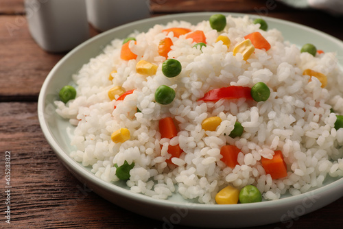 Delicious rice with vegetables on wooden table, closeup