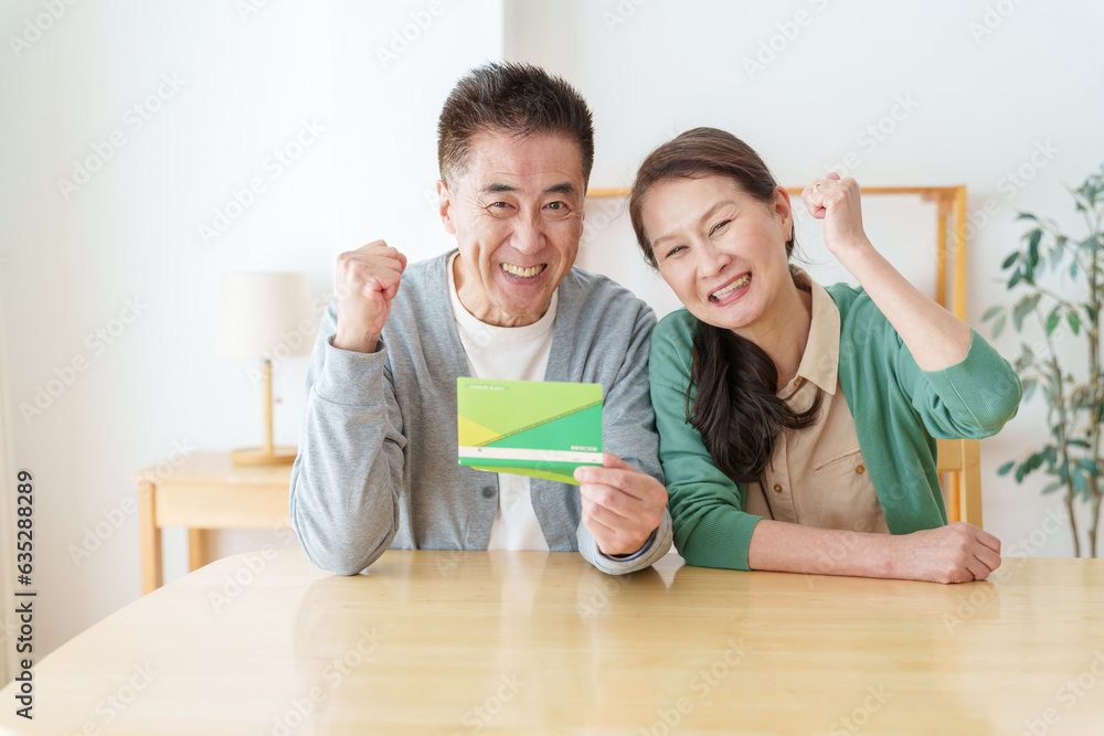 通帳を持ってガッツポーズをするシニア夫婦 通帳を持ってガッツポーズをするシニア夫婦