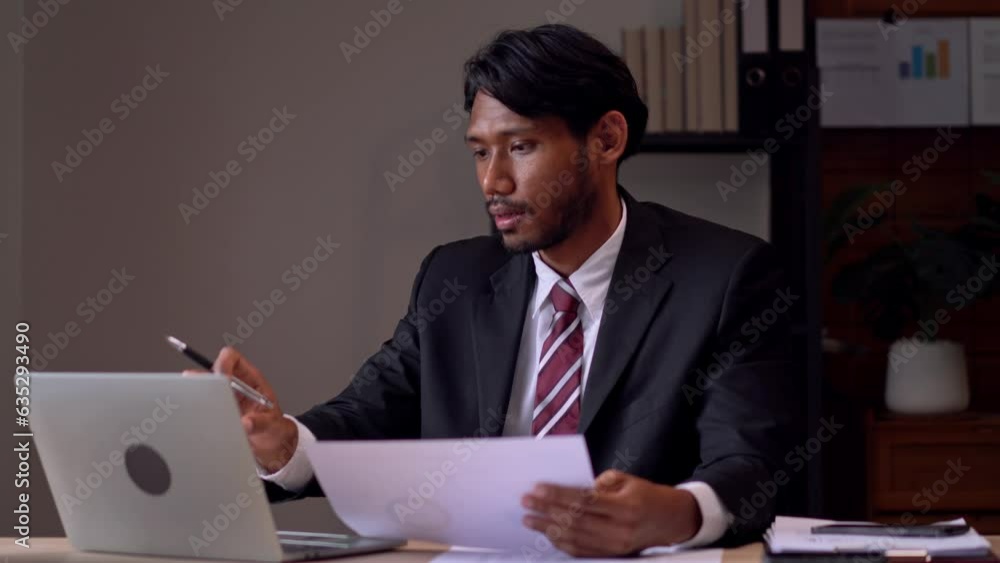 Asian businessman gesturing while doing video call talking on laptop consultant or telemarketing receptionist, worker in communication in modern coworking Asian businessman gesturing while doing video call talking on laptop consultant or telemarketing receptionist, worker in communication in modern coworking