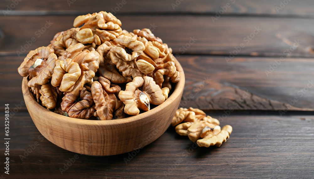 Walnut kernels in a wooden bowl on a dark wooden background. Close-up. Walnut kernels in a wooden bowl on a dark wooden background. Close-up.