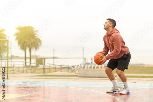 Young sporty man leaning to throw basketball ball.