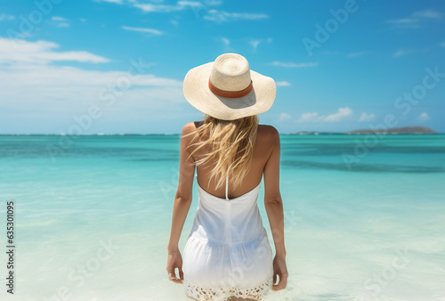Reverse photo of a woman in a white dress and hat by the ocean