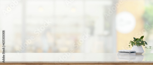 Copy space on a white tabletop with books and a potted plant on a blurred  bright background