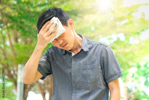 man working outside He had a headache and was dizzy. He used a handkerchief to wipe his sweat. because of hot weather