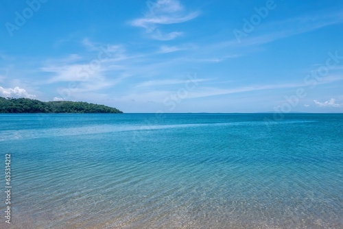 A beautiful calm turquoise sea and blue sky with wispy clouds, viewed from a beach in the tropical resort town of Puerto Galera, Philippines. photo