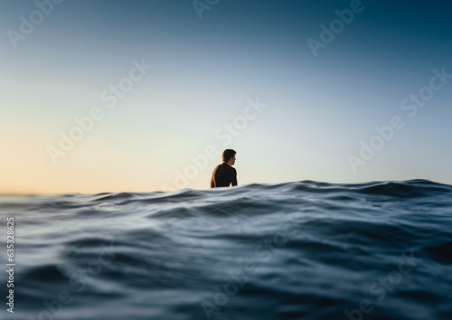 Male surfer being in a calm state while patiently waiting for a wave