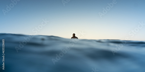 Male surfer being in a calm state while patiently waiting for a wave