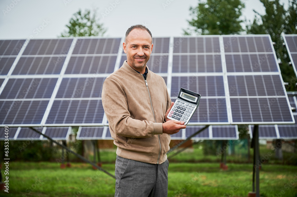 Knowledgeable man glad about his investment in green energy. Happy man showing his future profit from investing in solar panels. Knowledgeable man glad about his investment in green energy. Happy man showing his future profit from investing in solar panels.