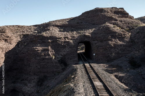 Train tracks going through tunnel opening photo