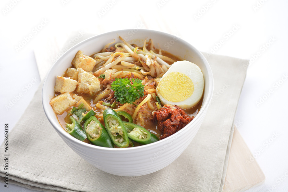 Malay mee rebus noodle with boiled egg, tofu, green chilli, sambal, vegetable, chilli sauce and hot thick spicy gravy soup in bowl on white background asian halal food cuisine menu for cafe design Malay mee rebus noodle with boiled egg, tofu, green chilli, sambal, vegetable, chilli sauce and hot thick spicy gravy soup in bowl on white background asian halal food cuisine menu for cafe design