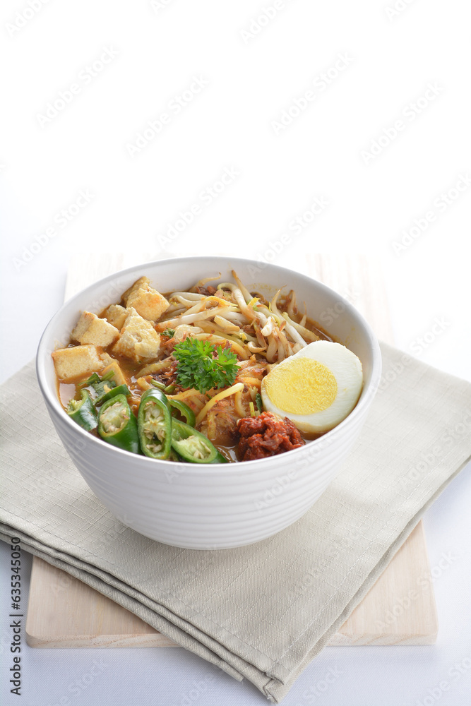 Malay mee rebus noodle with boiled egg, tofu, green chilli, sambal, vegetable, chilli sauce and hot thick spicy gravy soup in bowl on white background asian halal food cuisine menu for cafe design
