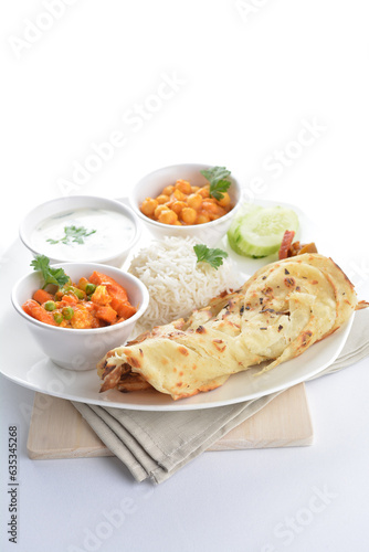 Indian traditional baked roti prata canai with curry vegetables, yogurt sauce, pea bean and steamed white rice  in plate on white background asian halal food vegan cuisine menu for cafe design