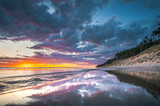 Baltic sea in colorful sunset colors with storm clouds. Turquoise water with waves, and sandy coastline.