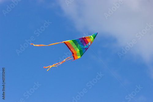 Rainbow kite on blue sky background.