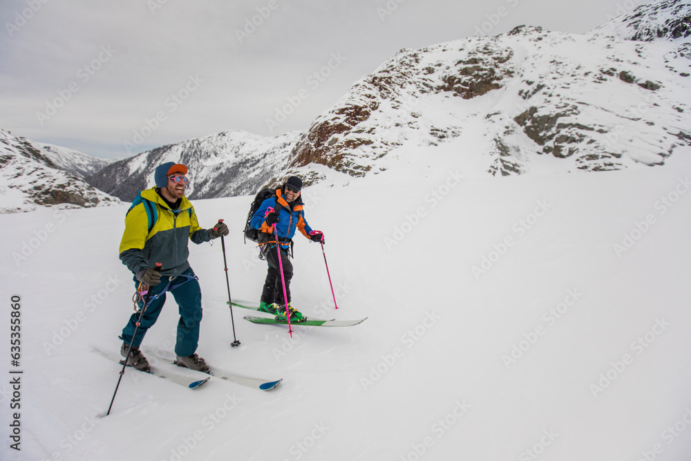 Friends laugh, smile and ski tour together outdoors Friends laugh, smile and ski tour together outdoors