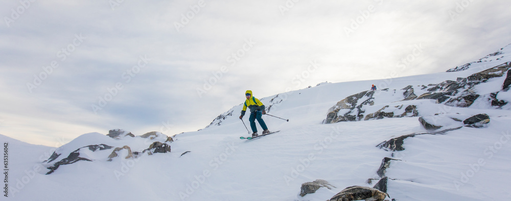 Skier descending from remote mountain summit Skier descending from remote mountain summit
