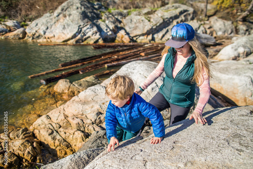 Mother and son climb on rocks near the shoreline, Vancovuer. photo