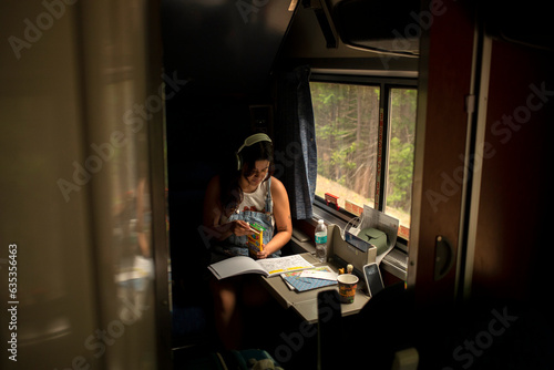 Young woman riding passenger train with coloring book photo