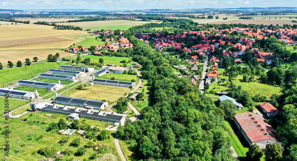 Aerial view of a modern farm with solar panels on the roofs in front of a village in the Harz mountains in Germany Aerial view of a modern farm with solar panels on the roofs in front of a village in the Harz mountains in Germany