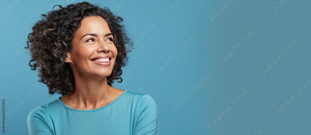 A Brazilian woman in her mid life presenting an idea with a smile while standing alone on a blue background